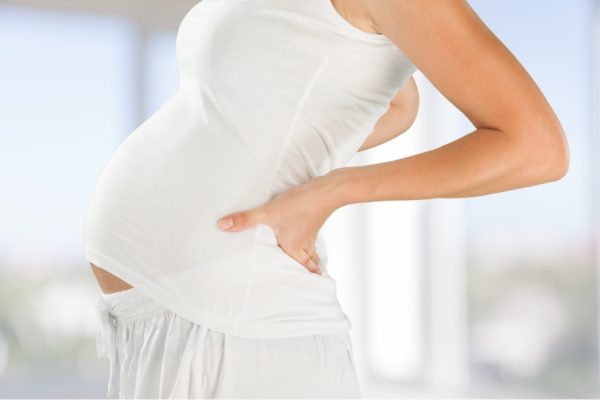 Femme enceinte soulageant mal de dos grossesse. Pregnant woman having backache